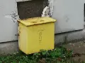 Żółta skrzynka gazowa w elewacji budynku, z napisem "UWAGA GAZ".
