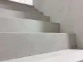 Nowoczesne schody z surowego betonu na klatce schodowej. Minimalistyczny design, jasnoszare stopnie.