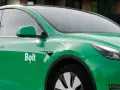 Zielone auto z oklejeniem Bolt. Widoczna część drzwi, lusterko i fragment maski.