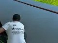 Pracownik w koszulce z logo "WORK-BUD" wykonuje posadzki żywiczne. Powierzchnia jest gładka, ciemnoszara, z pomarańczową linią.
