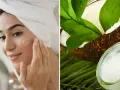 Mujer aplicándose crema en la cara, con un coco y un tarro de aceite de coco para la cara al lado.
