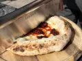 Ein Messer schneidet ein Stück Pizza mit geschmolzenem Käse und würziger Tomatensauce. Der luftige pizzateig napoli ist perfekt gebacken.