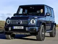 Ciemnoniebieski Mercedes G Klasa jedzie po pustynnej drodze. Kierowca uśmiecha się. Sprawdź mercedes g klasa cena!