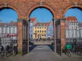 Kolorowe kamienice nad kanałem, idealne na szybkie zwiedzanie Kopenhagi w jeden dzień. Rowerzyści czekają na przejazd.
