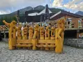 Drewniane rzeźby niedźwiedzi tworzą napis HREBENOK. W tle budynek z tarasem i góry. Sprawdź hrebienok kolejka cennik.
