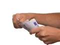 Dłonie trzymają banknoty euro. To może być symboliczne zawiadomienie o uchyleniu zajęcia, gdy pieniądze wracają do właściciela.