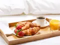 Taca z croissantami, truskawkami, kawą i sokiem pomarańczowym. Idealne wyżywienie HB na śniadanie do łóżka.