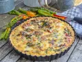 Herzhaftes Mangold Quiche Rezept, frisch gebacken und bereit zum Genießen. Bunte Mangoldstiele liegen daneben.