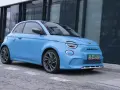 Niebieski Abarth 500e, gotowy do testów, zaparkowany przed nowoczesnym budynkiem.