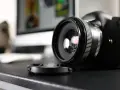 Czarne body lustrzanki cyfrowej z obiektywem i dekielkiem na czarnym blacie. Zastanawiasz się dslr co to? To właśnie to!