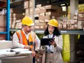 Due operai Bartolini in magazzino discutono dati su tablet, forse per calcolare lo stipendio camionista.