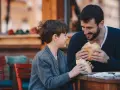 Vater und Sohn teilen sich ein Brot. Vielleicht plant der Vater ein Wechselmodell, um Unterhalt zu sparen, aber im Moment genießen sie die gemeinsame Zeit.