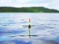 Spokojne jezioro Grabowo, łowiący wędkarz czeka na branie, widoczny spławik na falach.