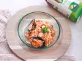 Delicioso arroz con pulpo y mejillones, servido en un cuenco de cristal sobre una tabla de madera.