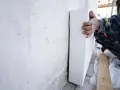 Mano di un operaio posiziona pannelli sottovuoto per isolare una parete grezza.
