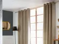 Eine schicke Gardinenstange anbringen, um die beige Vorhänge über dem Fenster zu befestigen. Dekorative Elemente wie Spiegel und Pflanzen ergänzen den Raum.
