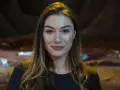 Uśmiechnięta Zuzanna Saporznikow z brązowymi włosami i kolczykami w kształcie kółek.
