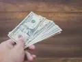 Dłoń trzyma plik banknotów dziesięciodolarowych. To może być zapłata za trzynastkę lub po prostu nagroda.