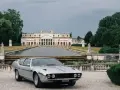 Srebrny Lamborghini Espada z lat 70. przed okazałą willą z basenem i rzeźbami.