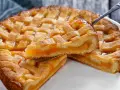 Deliziosa crostata senza glutine con ripieno di albicocche, la fetta sollevata mostra la morbidezza dell'impasto e la succosità della frutta.