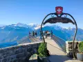 Tourists enjoy the breathtaking panorama from the Harder Kulm viewpoint, with snow-capped mountains under a clear blue sky.