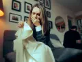 Verzweifelte Frau mit Lippenstiftabdruck auf Kleidung, die auf Ehebruch und möglichen Schadensersatz hindeutet. Ein Mann sitzt im Hintergrund.