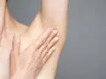 Hand berührt Achselhaut. Informationen zu Pickel unter Achsel Hausmittel.
