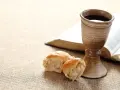 Kelch mit Rotwein, Brot und aufgeschlagenes Buch. Symbol für das christliche Abendmahl und dessen Bedeutung im Glauben.