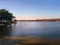 Spokojne jeziora w Małopolsce o zachodzie słońca. Drzewa na brzegu rzucają długie cienie na piaszczystą plażę.
