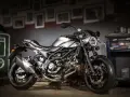 Srebrny motocykl Suzuki SV650X z czarną ramą i detalami, stojący w garażu.
