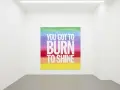 Œuvre de John Giorno dans une galerie, avec le message "YOU GOT TO BURN TO SHINE" sur un fond arc-en-ciel.