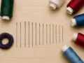 Un surtido de agujas de coser y carretes de hilo de colores: verde, morado, blanco, rojo y azul. ¡Qué hilo de hilo tan variado!