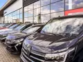 Rząd nowych samochodów na placu. W tle budynek salonu Dacia. Sprawdź autoplac opinie przed zakupem.