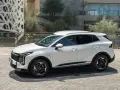 Biała Kia Sportage hybryda na tle nowoczesnej architektury. Stylowy SUV gotowy na miejskie wyzwania.