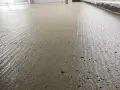 Świeżo wylany, wilgotny **pianobeton** na budowie, z widocznymi śladami po zacieraniu i drobnymi pęcherzykami powietrza.