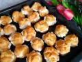 Pyszne ciasto na ptysie, wypełnione kremem, czeka na spróbowanie. Obok piękne tulipany.