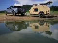 Srebrny Ford Raptor z przyczepą wyprawową Lifestyle Camper nad jeziorem.