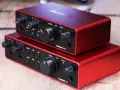 Dwa czerwone interfejsy audio Focusrite Scarlett Solo 3gen i Scarlett 2i2 ułożone jeden na drugim.