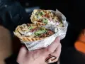 Pyszny kebab z Bukowiny Tatrzańskiej, pełen mięsa, warzyw i sosu, zawinięty w papier z gazetowym nadrukiem.