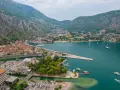 Widok na zatokę z górami w tle, miasto Kotor w Czarnogórze, z łodziami i budynkami.