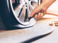 Mano che gonfia una gomma di un SUV, controllando la pressione gomme suv per un viaggio sicuro.