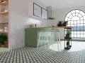 Cocina moderna con azulejos blancos en rombos como materiales para cubrir paredes, encimera de madera y suelo con patrón geométrico verde.