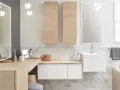 Salle de bain moderne avec un lavabo évier suspendu, des meubles en bois clair et un grand miroir éclairé.