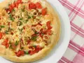 Pizza casera con tomates, queso derretido, cebolla y cebollino. Los ingredientes de esta pizza casera lucen deliciosos.