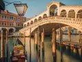 Gondola ferma in un canale di Venezia inverno, con il Ponte di Rialto sullo sfondo.