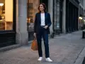 Kobieta w granatowej marynarce i jeansach, z brązową torbą, prezentuje styl semi formal na ulicy.