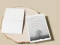 Zwei Postkarten liegen auf einem Holzstamm. Eine zeigt einen einsamen Baum im Nebel und den Spruch: "Der Herr ist denen nahe, die verzweifelt sind und rettet diejenigen, die alle Hoffnung verloren haben.