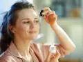Kobieta aplikuje serum z **retinalem** na skórę pod okiem, dbając o młody wygląd.