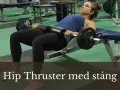 Kvinna utför hip thrust med stång på en bänk i ett gym.