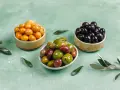 Tres cuencos con aceitunas de diferentes colores: amarillas, verdes y negras.